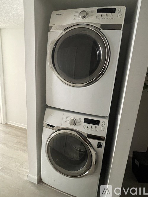 Two white front loading washing machines stacked on top of each other.