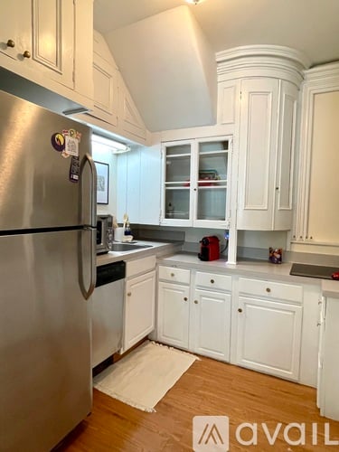 A kitchen with a stainless steel refrigerator and white cabinets.