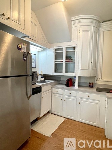 A kitchen with a stainless steel refrigerator and white cabinets.