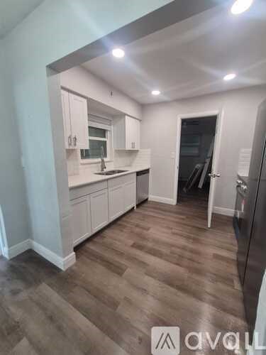 A kitchen with wooden floors and white cabinets.