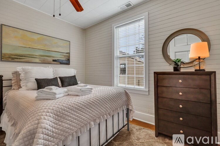 A bedroom with a bed, a dresser, and a painting on the wall.