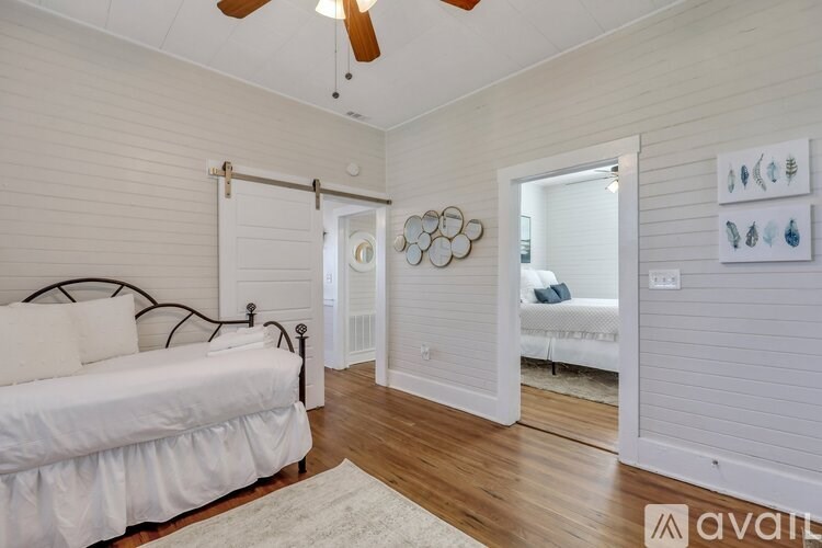 A bedroom with a bed, a ceiling fan, and a wall with pictures.