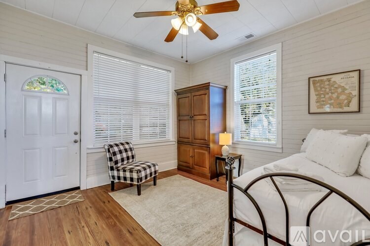 A bedroom with a bed, chair, and a ceiling fan.