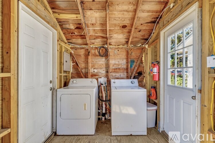 A room under construction with a wood ceiling and walls, a white door, a window, and a washing machine.