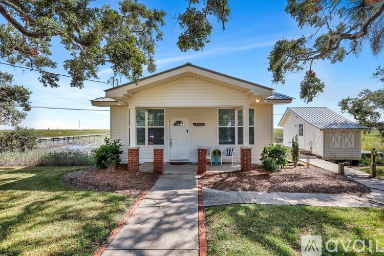 A small house with a front porch and a driveway leading to the front door.