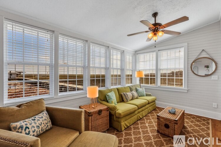 A living room with a green couch and a fan on the ceiling.