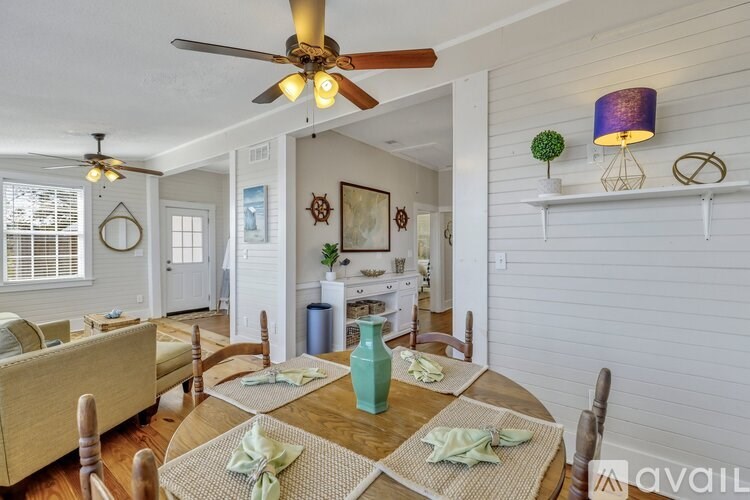 A dining room with a table set for two and a ceiling fan.
