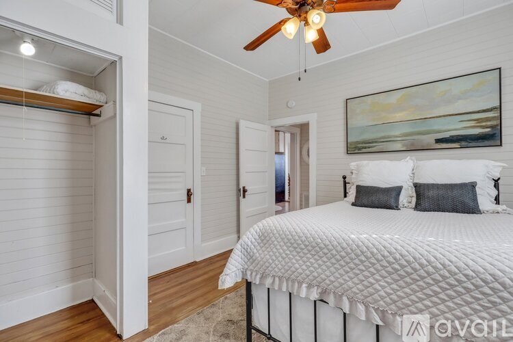 A bedroom with a large bed and a ceiling fan.