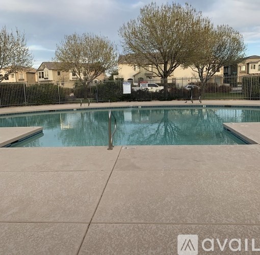 A pool surrounded by a black fence with a sign that says "available" in the background.