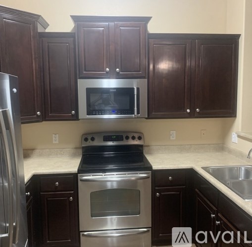 A kitchen with dark wood cabinets and stainless steel appliances.