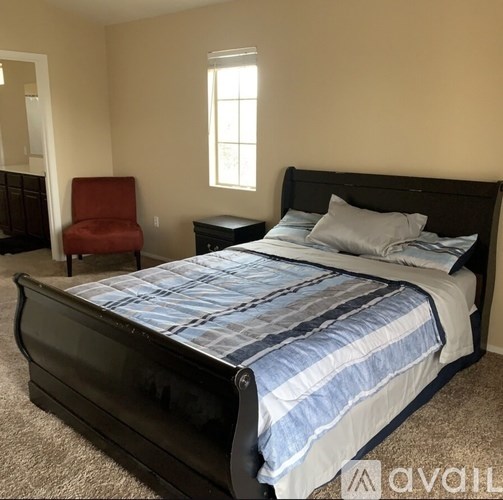 A bedroom with a large bed and a red chair.