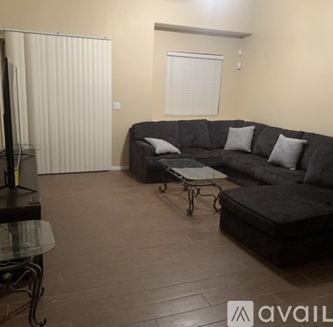 A living room with a grey couch and a glass table.