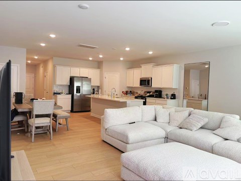 A modern kitchen and living room with white furniture and wooden floors.