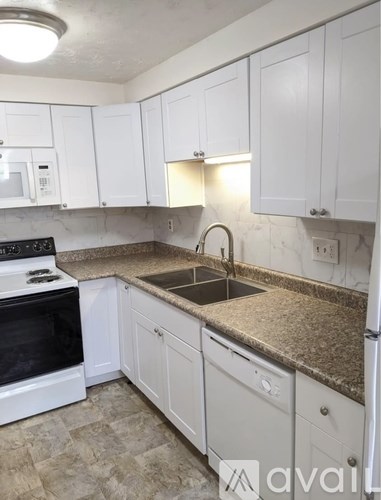 A kitchen with white cabinets and granite countertops.
