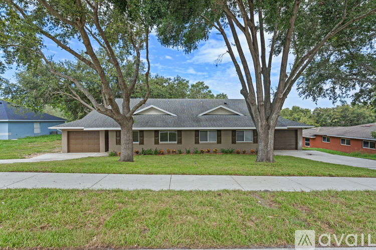 A house with a brown roof and a tree in front of it.