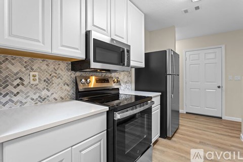 A kitchen with white cabinets and a black refrigerator.