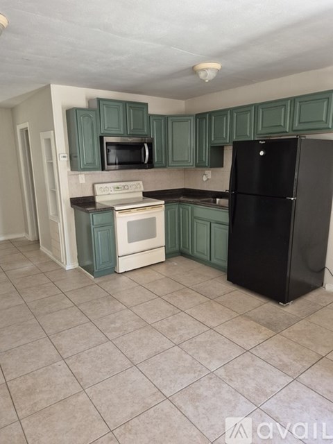 A kitchen with green cabinets and black appliances.