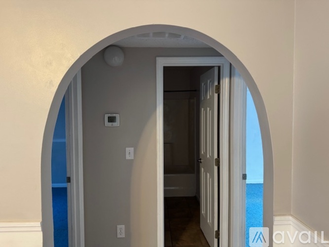 A room with a white door and a window showing a blue sky.