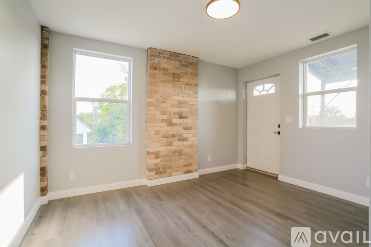 A room with a brick wall and wooden flooring is available for rent.