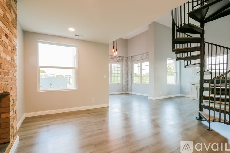 A spacious room with a brick wall and a spiral staircase.