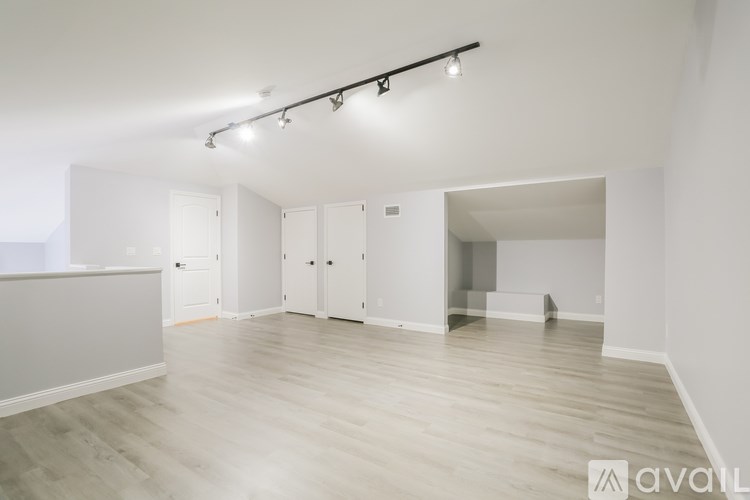 A spacious room with wooden flooring and white walls.