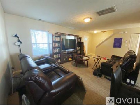A living room with a brown leather couch and a television.