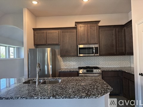 A kitchen with a granite countertop and dark brown cabinets.