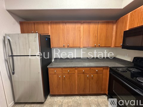 A kitchen with wooden cabinets and a stainless steel refrigerator.