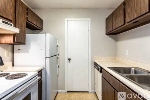 A kitchen with white appliances and wooden cabinets.
