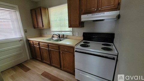 A kitchen with wooden cabinets and a white stove top oven.