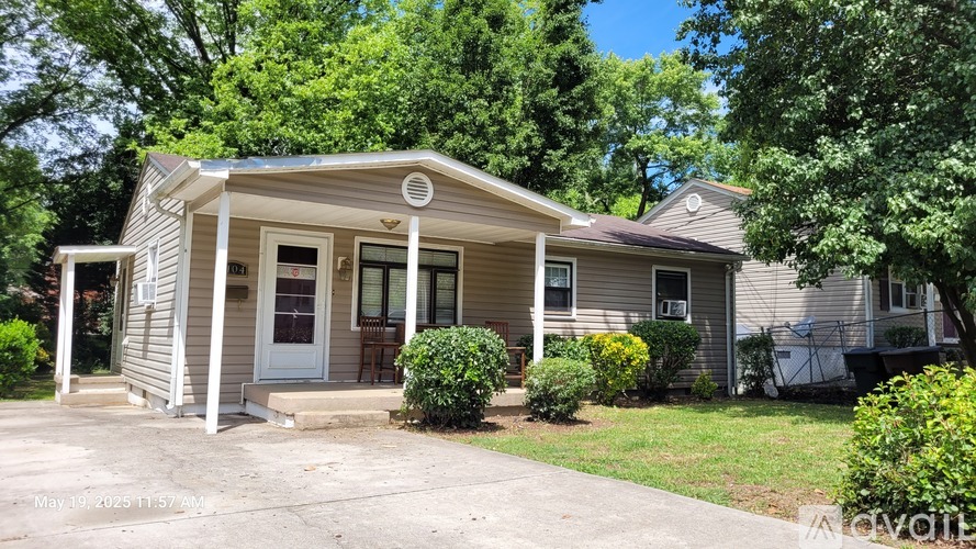 A house with a porch and a tree in front.