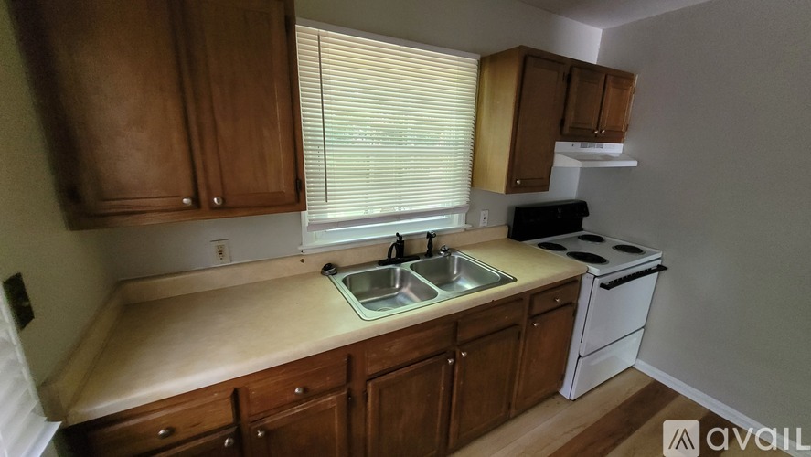 A kitchen with wooden cabinets and a white stove top oven.