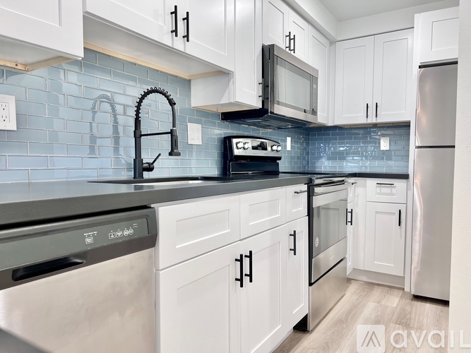 A kitchen with white cabinets and a black countertop.