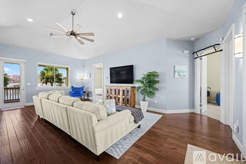 A living room with a beige couch and a ceiling fan.