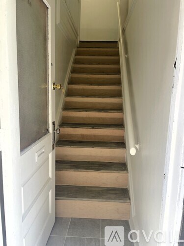 A set of stairs with a white door on the left.
