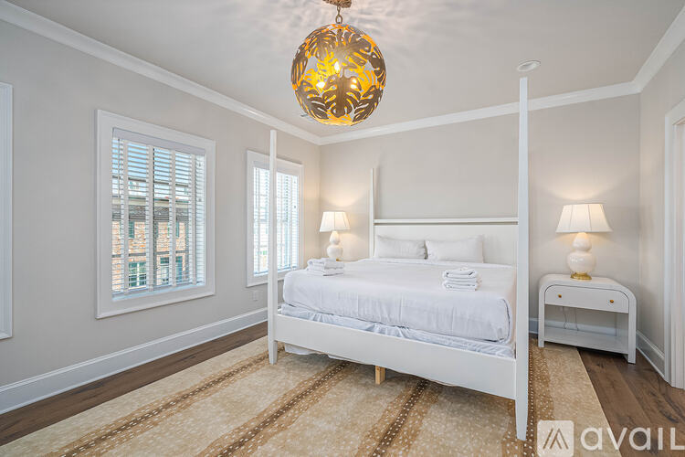 A bedroom with a large bed and a chandelier hanging from the ceiling.