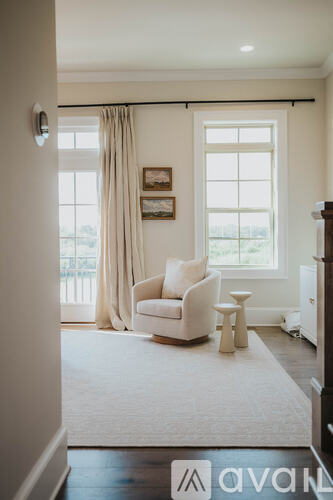 A living room with a white chair and a window.