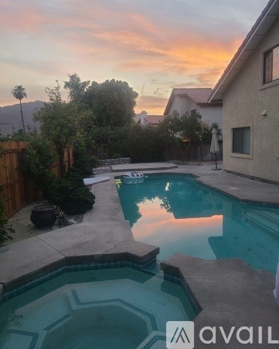 A pool surrounded by a patio and a house.