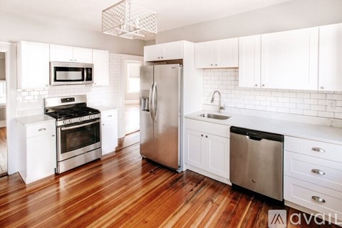 A kitchen with white cabinets and a wooden floor.