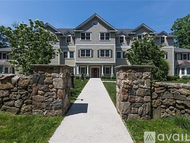 A large house with a stone wall and a pathway leading to the entrance.