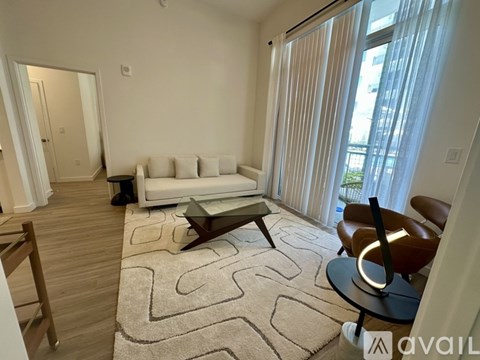 A living room with a white couch, a coffee table, and a rug with a maze pattern.