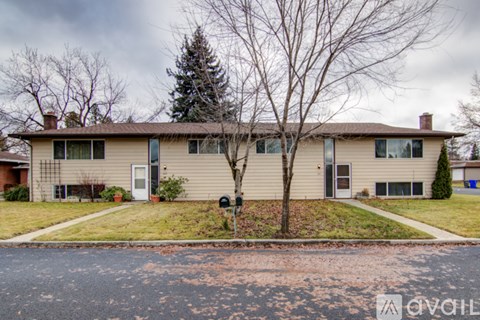 A house with a brown roof and a tree in front of it.