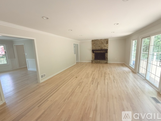A spacious room with wooden flooring and a fireplace.