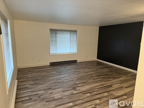 A room with wooden flooring and a window with blinds.