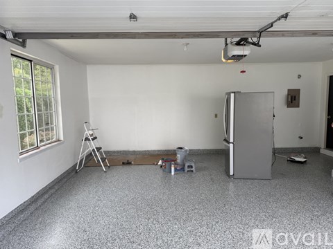 A room with a grey floor, white walls, and a window with a view of trees.