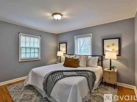 A bedroom with a bed, two lamps, and two pictures on the wall.