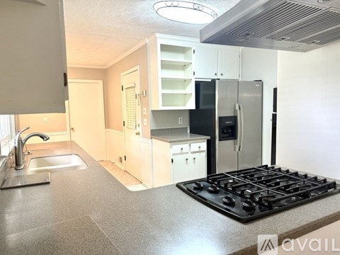 A kitchen with a black stove top and a white fridge.