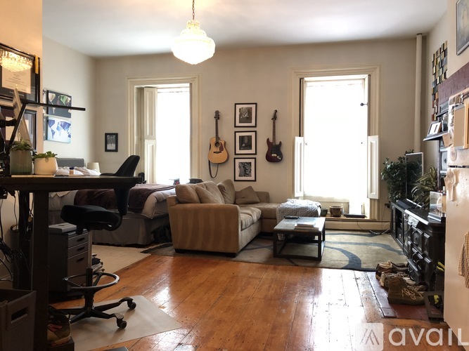 A living room with a couch, a chair, a guitar, and a piano.