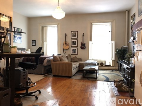 A living room with a couch, a chair, a guitar, and a piano.