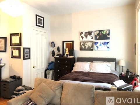 A bedroom with a bed, dresser, and wall art.